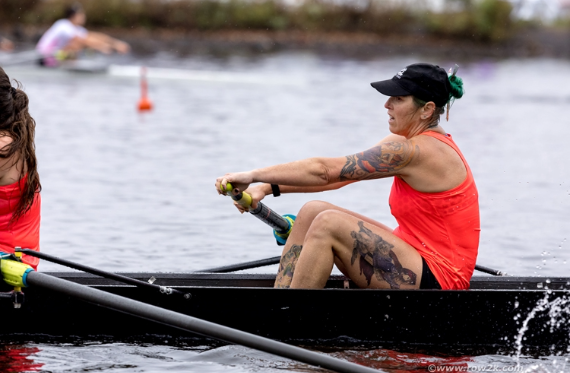 Cindy sits in a competitive rowing boat, rowing forward with her team.
